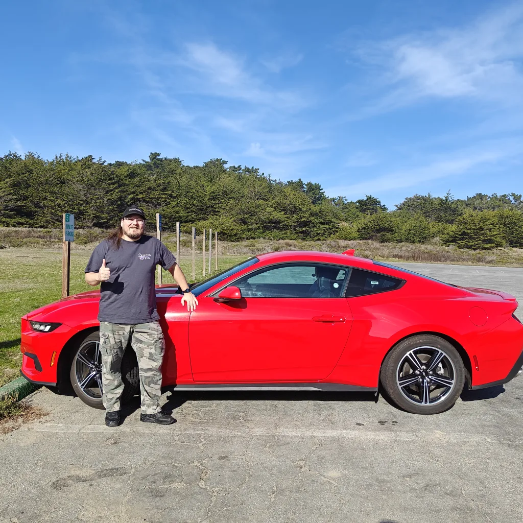 Me standing in front of a red mustang I rented giving a thumbs up.